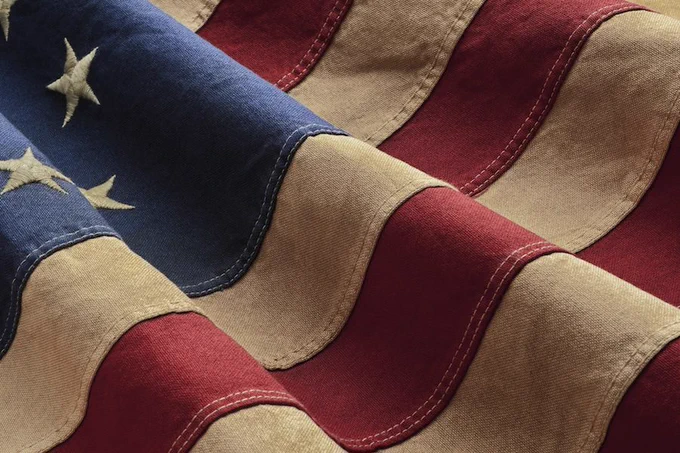 Close-up of a vintage American flag, highlighting its textured stripes and stars.