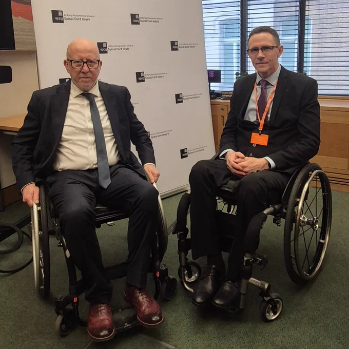 Andy McDonald in a wheelchair with Glyn Hayes of Spinal Injuries Association.