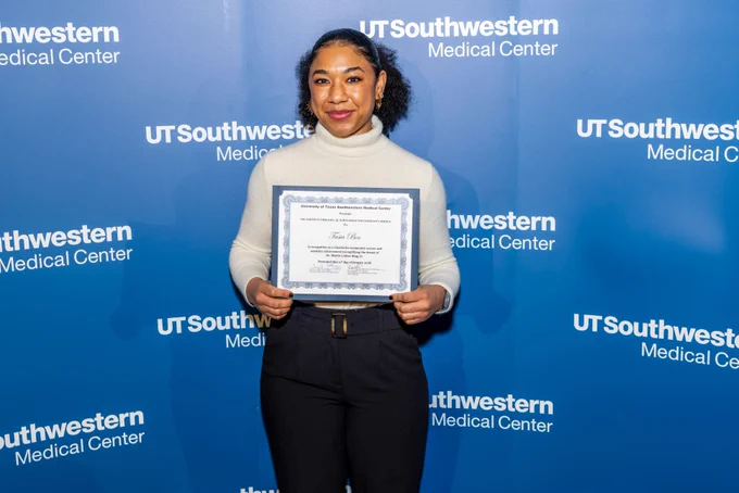 Person holding a certificate in front of a UT Southwestern Medical Center backdrop.