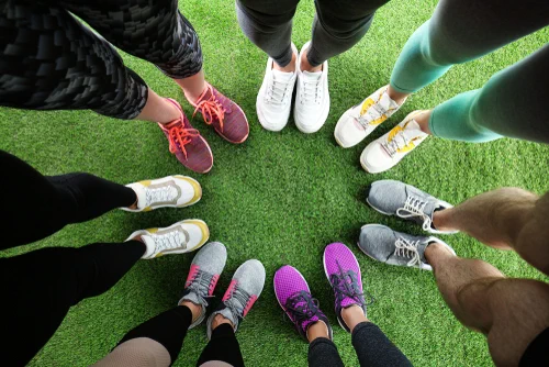 Circle of people showing their sports shoes.
