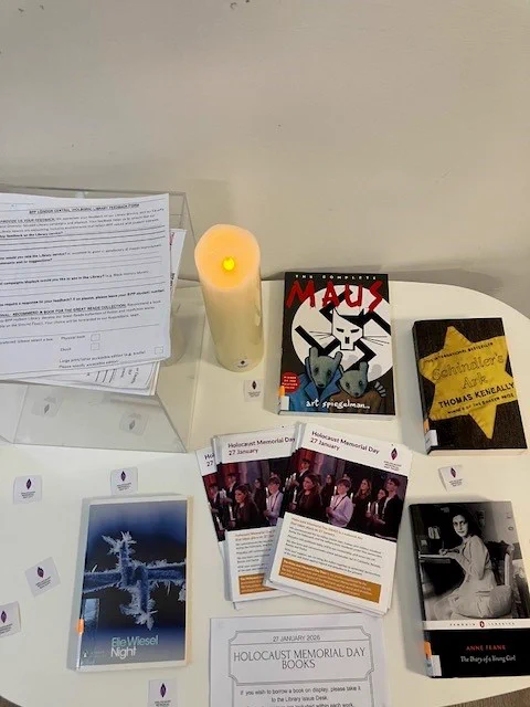 A photo of the BPP Holborn Library Space of Reflection-a series of books chosen to commemorate Holocaust Memorial Day are shown face up on a white table that also displays guidelines and information on the Space of Reflection, and a white commemorative non-flammable electronic candle (switched on to emit a candle-like glow). Books, clockwise from left to right: ‘Night’ by Elie Wiesel, ‘Maus’, a graphic novel by Art Spiegelman, ‘Schindler’s Ark’ by Thomas Keneally, and ‘The Diary of a Young Girl’ by Anne Frank. 
