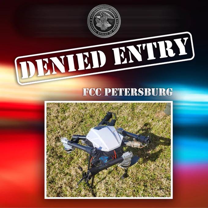 Image showcasing an 'FCC Petersburg Denied Entry' sign above a drone lying on grass.