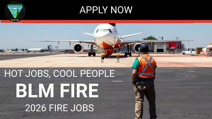 Aircraft attendant in safety gear watches a large firefighting aircraft on runway preparing for takeoff.