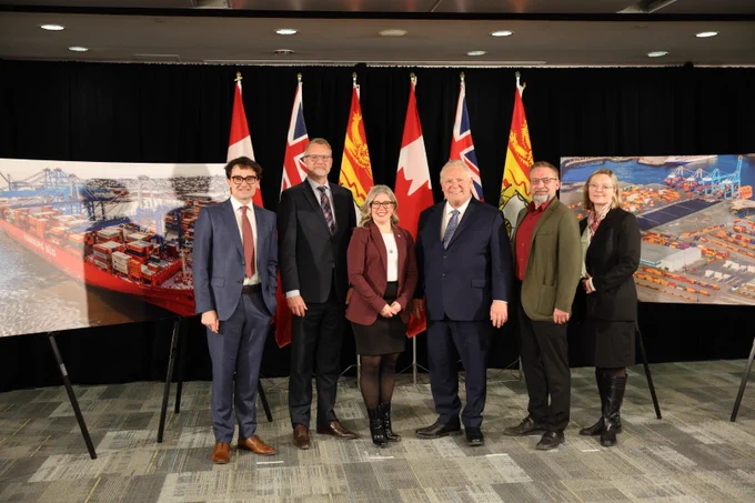 Premier Holt speaks at a podium labeled "Protect Ontario" as several people, including Ontario Premier Doug Ford, stand behind her. Multiple Canadian provincial flags are displayed in the background.