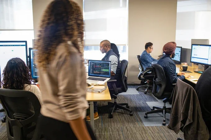 Image of people working on computers in an office space.