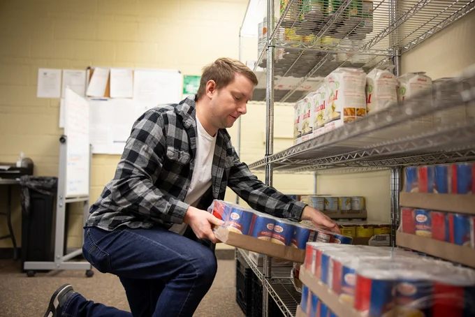 Individual stocking shelves in on-campus food pantry.