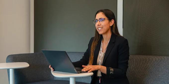 A person sitting at a table in an office using a laptop.