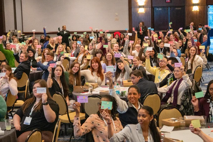 Attendees raising their cards at the Women in Atmospheric Sciences luncheon.