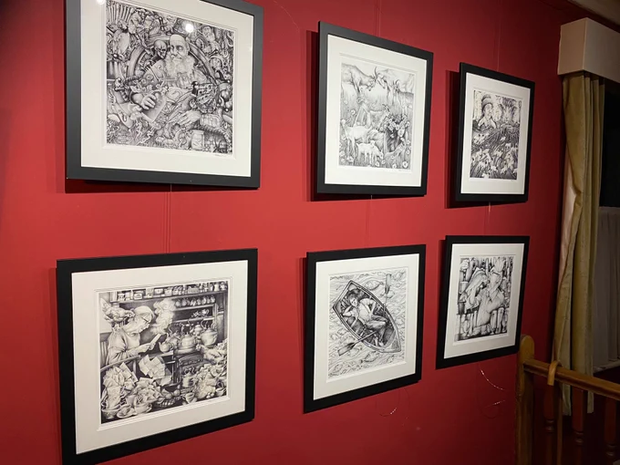 6 framed illustrations of Under milk wood hang on the deep red wall by the stairs.