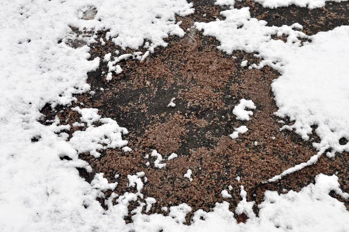 Grit on a driveway, surrounded by melting snow