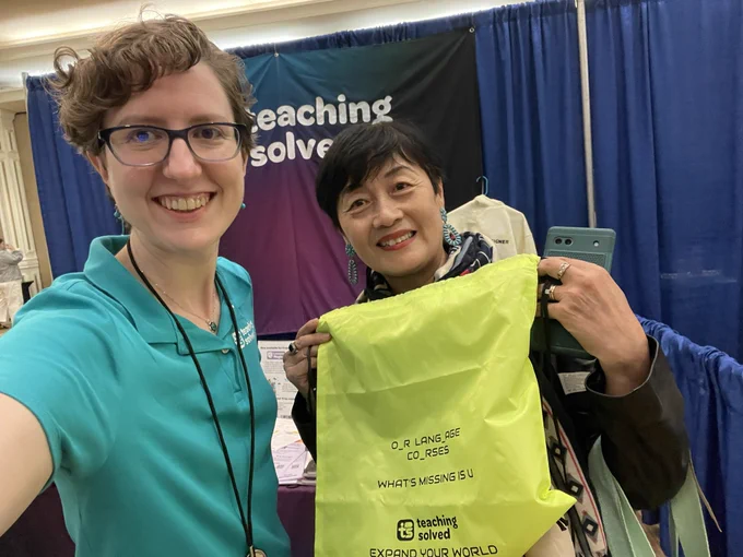 Hope with a teacher holding up a teaching solved bag in front of the teaching solved booth