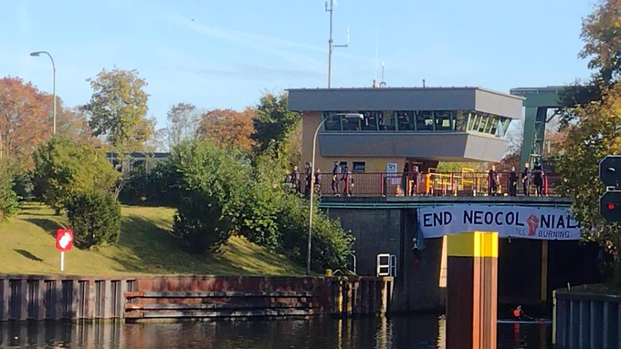 Bild aus der Entfernung der Schleuse. Mehrere Polizist*innen stehen neben der Blockade.