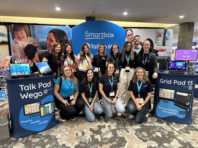 Large group of adults posing in front of their conference booth