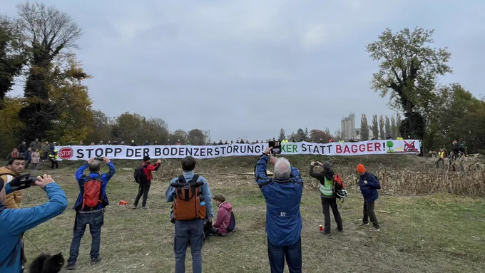 Riesenbanner in der Au „Stopp der Bodenzerstörung. Acker statt Bagger!“ vor der geschlägerten Schneise in der Fischa-Au.