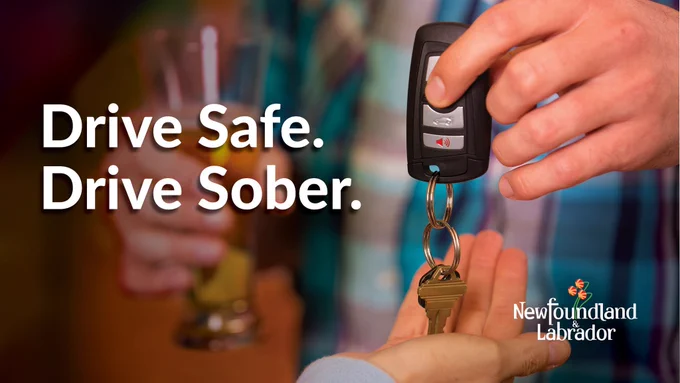 A person is passing a set of car keys to another person and in the background, another person is holding a glass of beer.