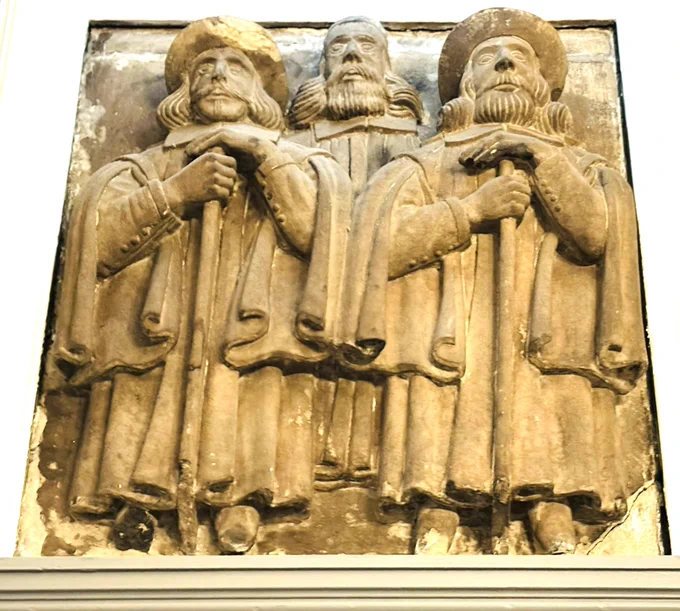Photo of a carved stone panel depicting three men in robes.