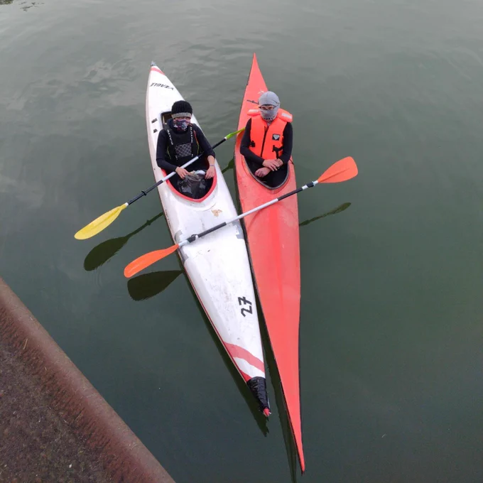 Zwei Kayaks mit Menschen darin, die nebeneinander liegen.