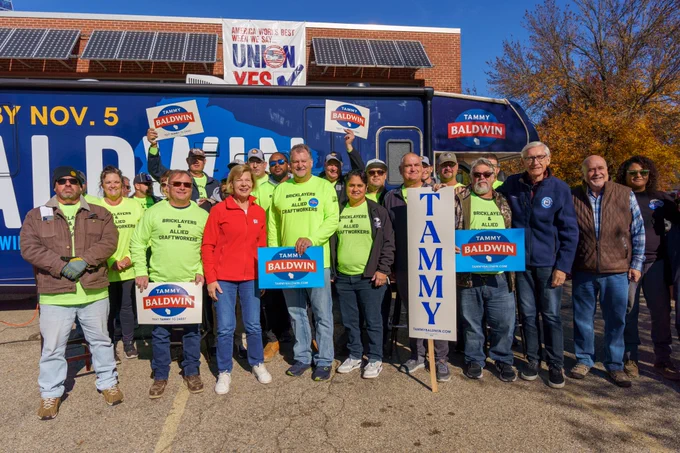 Tammy Baldwin and Tony Evers pose for a group photo with supporters outside of the Tammy Baldwin RV.