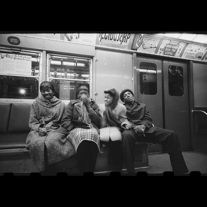 Four young subway riders sharing a laugh.
