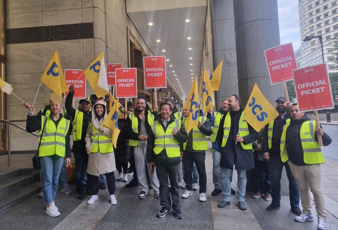 Big group of people in high vis with flags and placards under the colonnade at 10 South Colonnades.