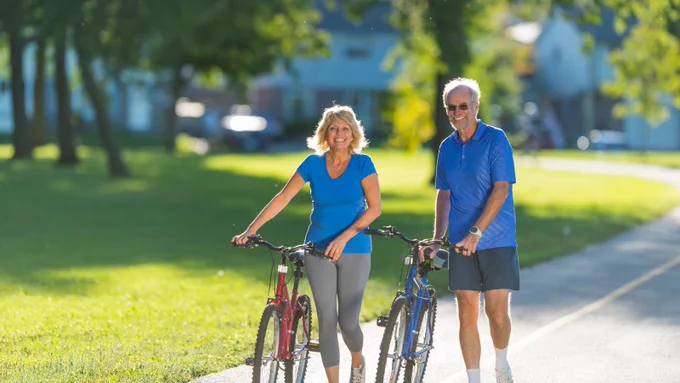 A woman and a man wheeling bikes on a cycle lane.