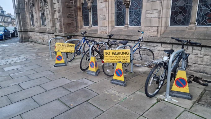 A number of bolted-down Sheffield Stands in Leith - with bikes currently locked to them - feature several yellow council signs warning of disruption to parking for their reinstatement on a particular day.