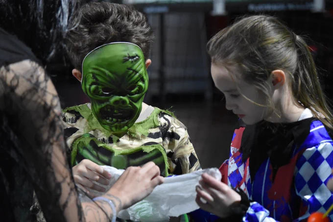 Two players dress in halloween outfits inspecting an object.