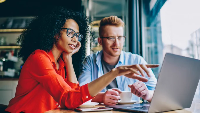 Stock image of two people viewing a laptop.