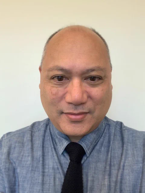 The photo is a headshot of Don Operario wearing a blue shirt and black tie. Photo courtesy of Don Operario,