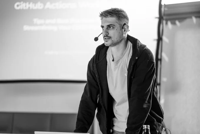 Thorsten Frommen during his talk with a slide saying "GitHub Actions Workflows" on the screen in the background