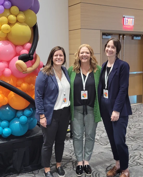 Image Description: NDSGC Director, Assistant Director, and Associate Director pose with a balloon arch themed in the Multicultural Conference symbol.