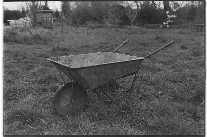 A black and white photo of a wheelbarrow on a grassy field