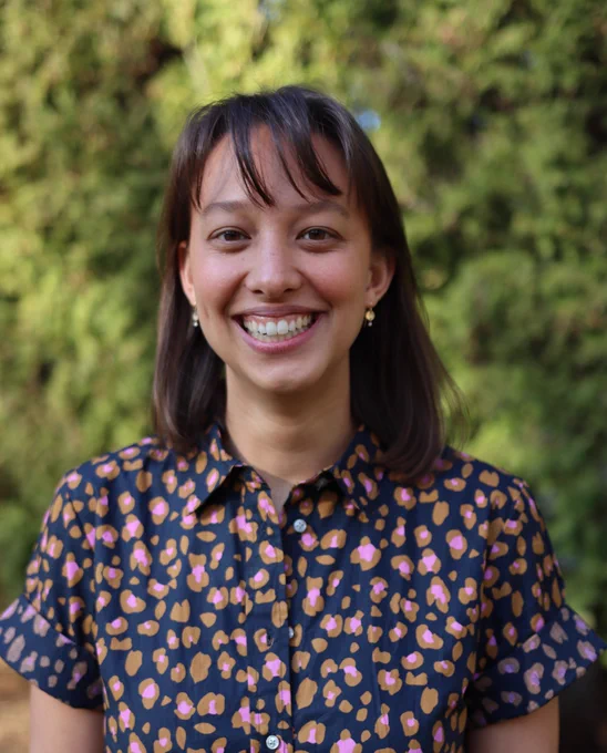 A scholar with green trees in the back ground and a floral shirt in blue/pink colors.