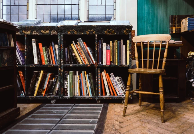 A chair and low bookcases beneath a window