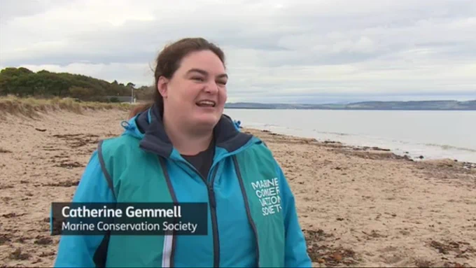 Screenshot of Catherine on Nairn beach wearing a marine Conservation society beach clean tabard 