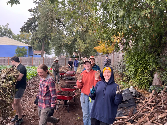 smiling people hauling wheelbarrows of garden soil