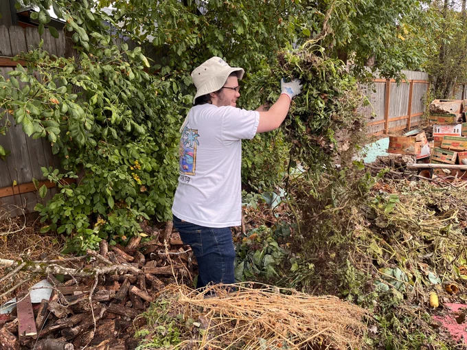 smiling person throwing branches onto a pile 
