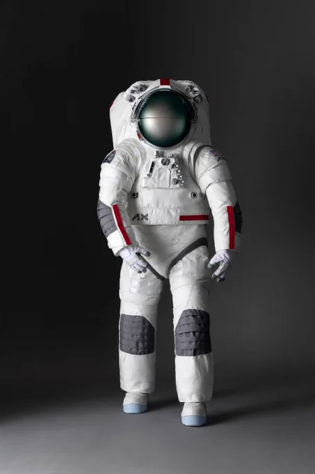 A mockup of the Axiom Space lunar spacesuit design. The majority of the spacesuit is white with grey patches over the knees and elbows and red trimming on the sleeves and torso. Credit: Axiom Space