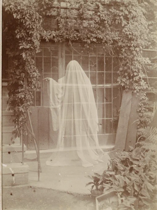 Black and white photograph with faint ghostly figure covered in a white sheet. 