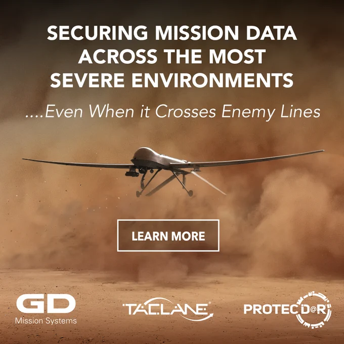 Advertisement featuring a drone flying low over a dusty terrain with text promoting General Dynamics Mission Systems' reliable data security across severe environments, including 'SECURING MISSION DATA ACROSS THE MOST SEVERE ENVIRONMENTS...Even When it Crosses Enemy Lines'. Logos for General Dynamics, TACLANE, and PROTECTOR are displayed at the bottom.