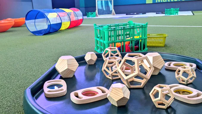 A photograph of various baby toys and equipment laid out on the AstroTurf floor of the Pitch Gallery.
