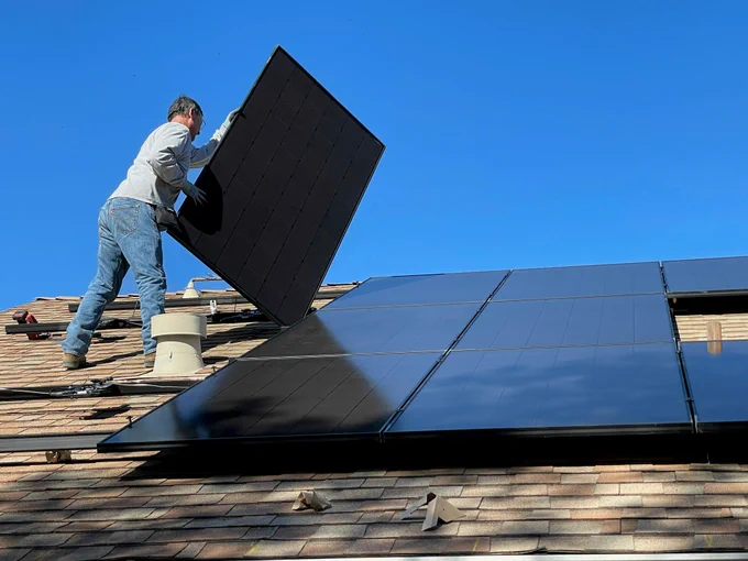 Tradesman installing solar panels on a roof.