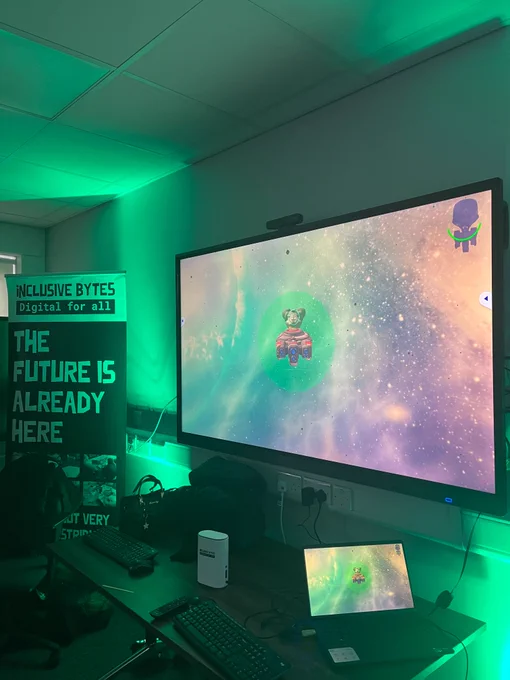 A banner displaying information about Inclusive Bytes stands next to a screen displaying a video game.