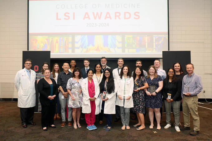 Group of individuals posing with awards at the LSI Awards 2023-2024 event in front of a screen displaying the event's name.
