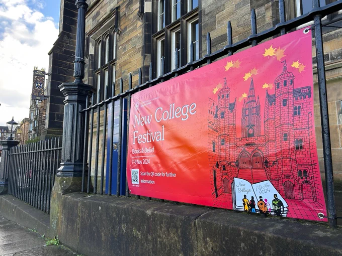 Colour photo of the New College Festival banner placed on the railings outside the New College building