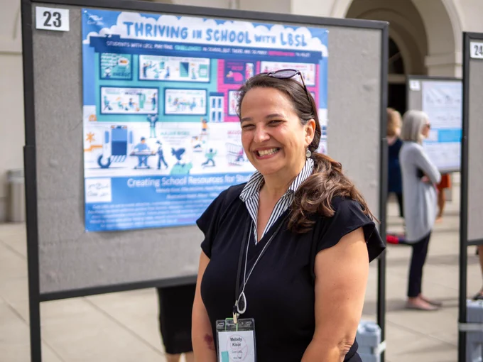 Person standing in front of poster smiling