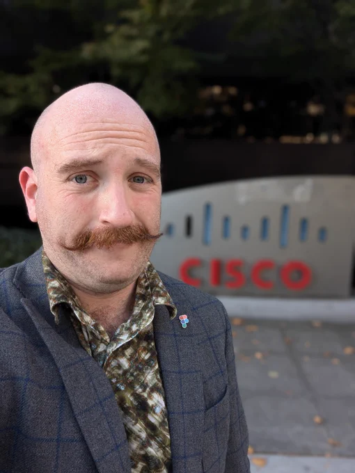 Selfie of Joe with a curly mustache in front of the Cisco Seattle sign