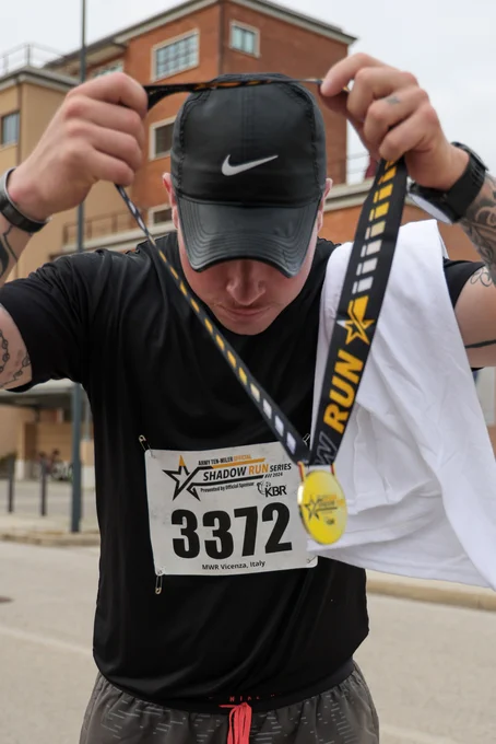 U.S. Army Soldier puts on a medal after completing the Army Ten-Miler shadow run at Caserma Del Din, Vicenza, Italy, Oct. 16, 2024. The shadow run mirrors the Army Ten-Miler held annually in Washington D.C., providing an opportunity for service members and civilians stationed overseas to participate, fostering camaraderie and physical fitness. (U.S. Army photo by Sgt. Ashley Fletcher) 