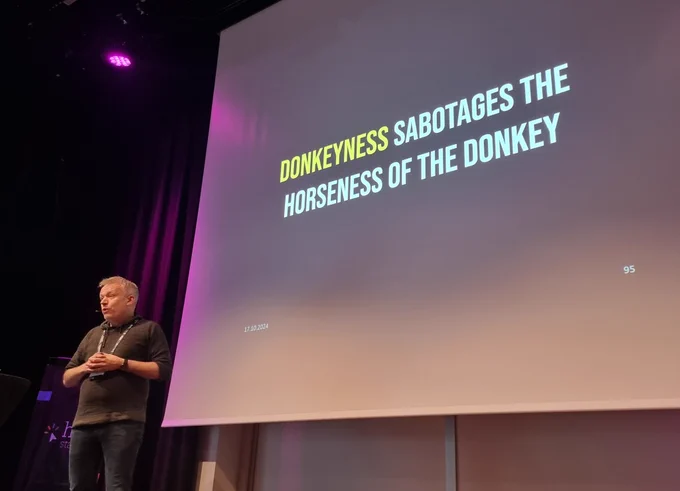 Einar on stage with the slide behind him, saying "Donkeyness sabotages the horseness of the donkey" 