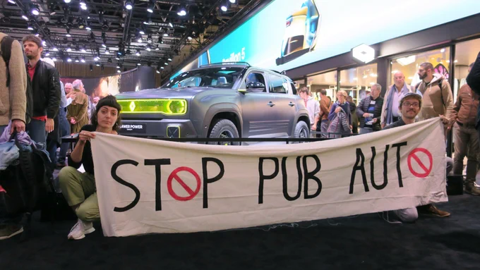 Photographie des activistes de R.A.P. avec une banderole ou il est écrit « Stop Pub Auto » devant le Stand de la Fl4wer Power de Renault (SUV)